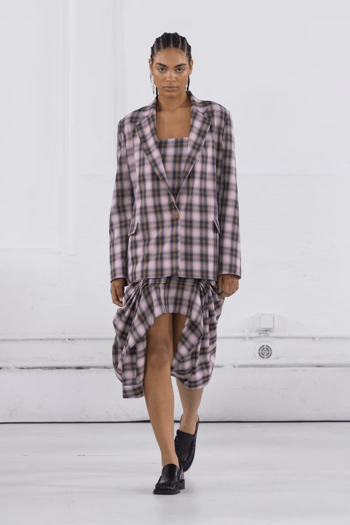 Model wearing Mossi SS25 collection a plaid blazer and matching dress, showcasing a modern take on checkered patterns in a stylish setting.