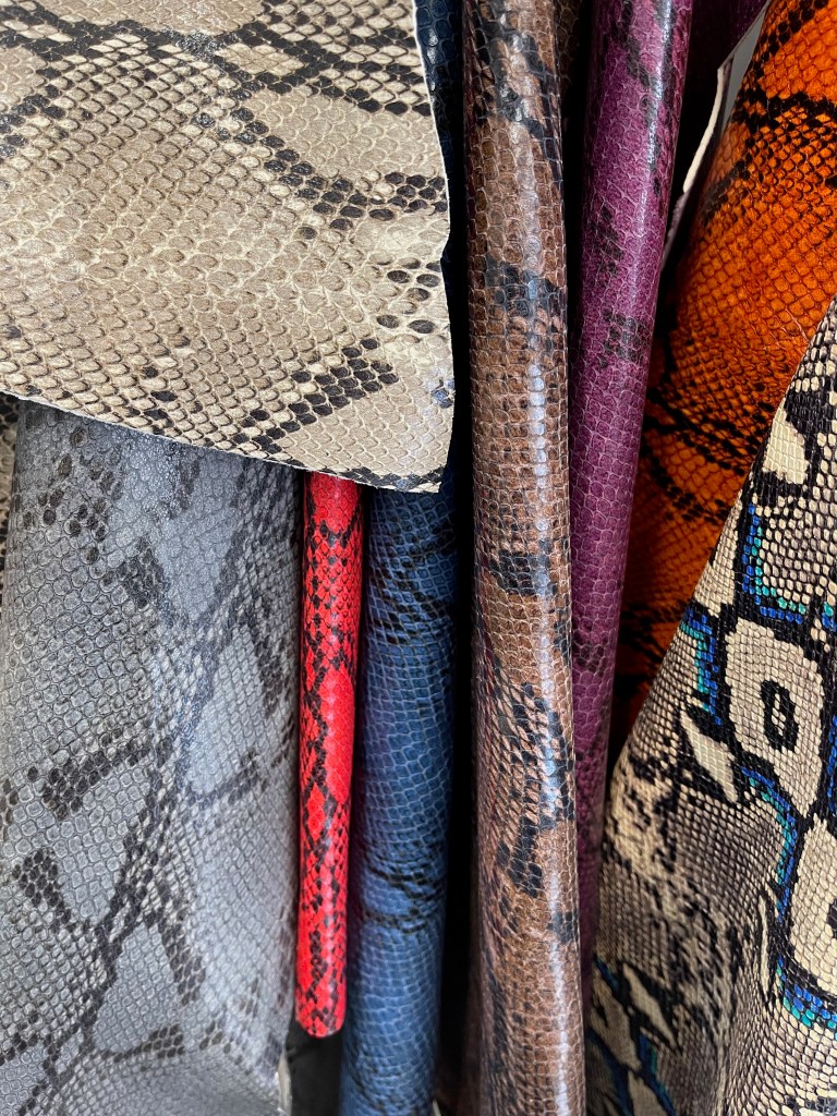 A close-up view of various snake-patterned fabrics in different colors and textures  in Seonsu-dong material market.