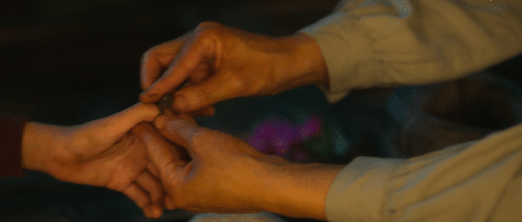 Close-up of two hands, one an older adult and the other a child's, colouring nails with peach petals