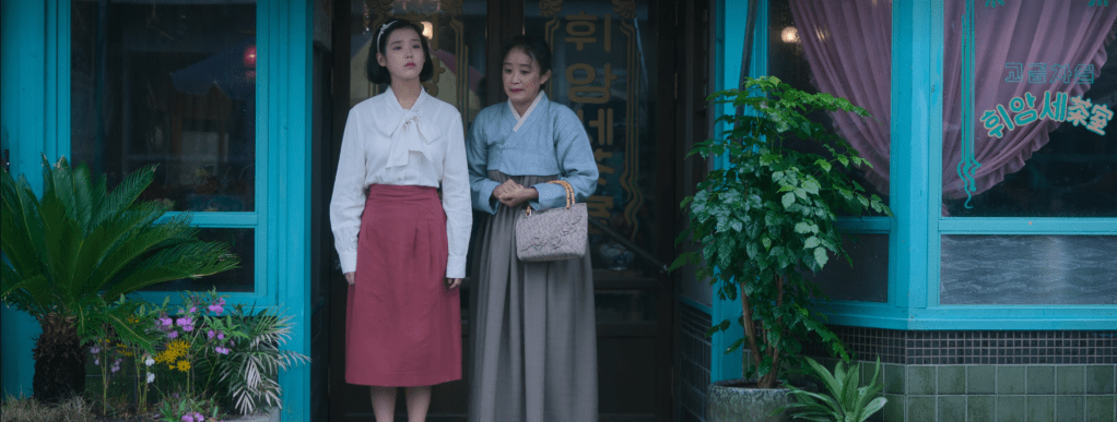 Aesun and her aunt standing outside of a coffee shop where Aesun had a blind date with a divorced man with two kids for marriage after she returned to Jeju from running away with Gwansik