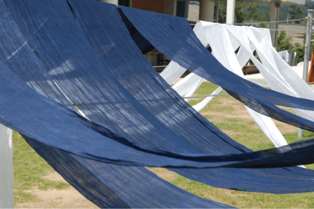 korean traditional colour Indigo Blue(Jjok) and white fabric draped on a clothesline in a grassy area.