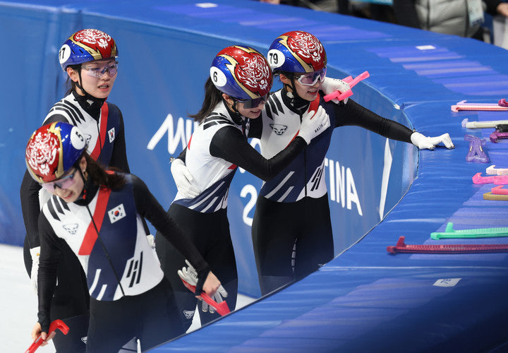 Gold medal team, four South Korean female short track speed skaters in matching uniforms and helmets, with Korean flags in 2026 Milano Cortina winter olympics.