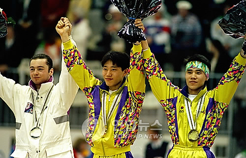 The Gold medalist Kim ki-hoon celebrating on a podium, raising his hands in 1992 Albertville Games.