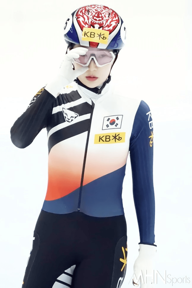 Lee So-yeon speed skater wearing a colorful racing suit and helmet, adjusting her goggles while in a focused pose.
